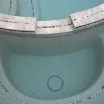 Close-up of a blue swimming pool with a curved edge made of tiles.