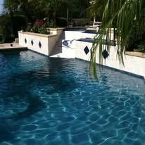 A rectangular swimming pool with blue water and decorative tiles on the sides.