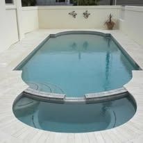 Swimming pool with a curved edge and rounded steps, surrounded by white tile.