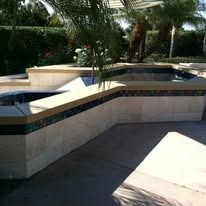 Raised spa with tan stone and mosaic tile trim, in an outdoor setting.