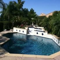 Swimming pool with cascading levels, surrounded by landscaping, under a sunny sky.