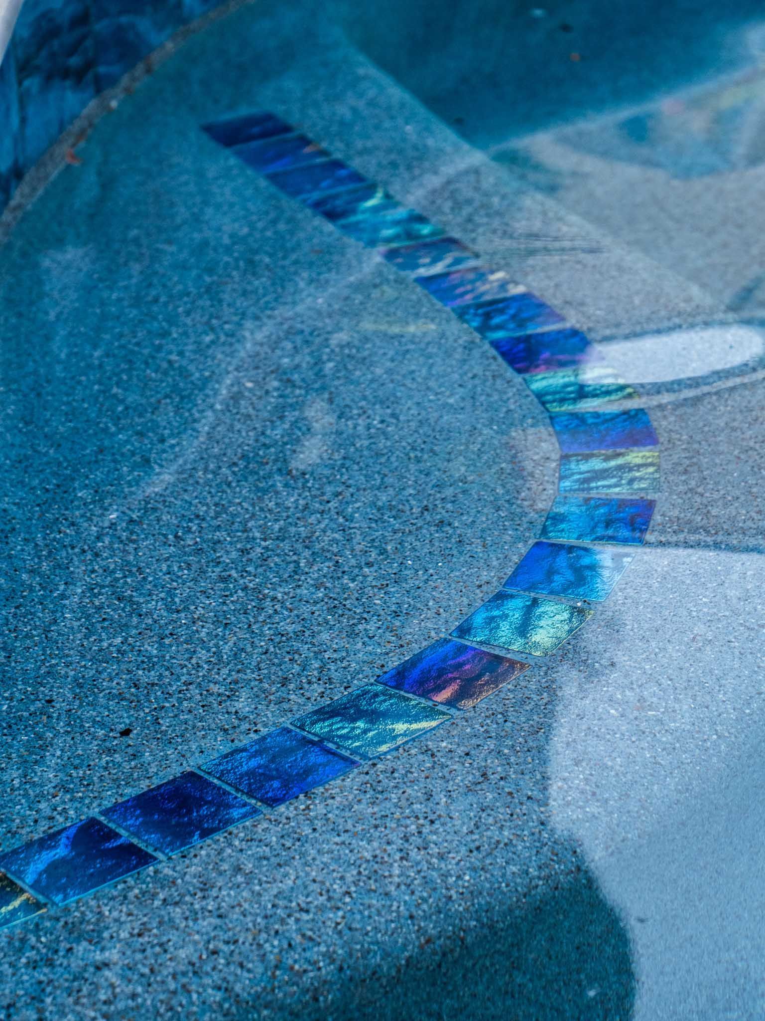 Blue tiled pool steps with a mosaic border.