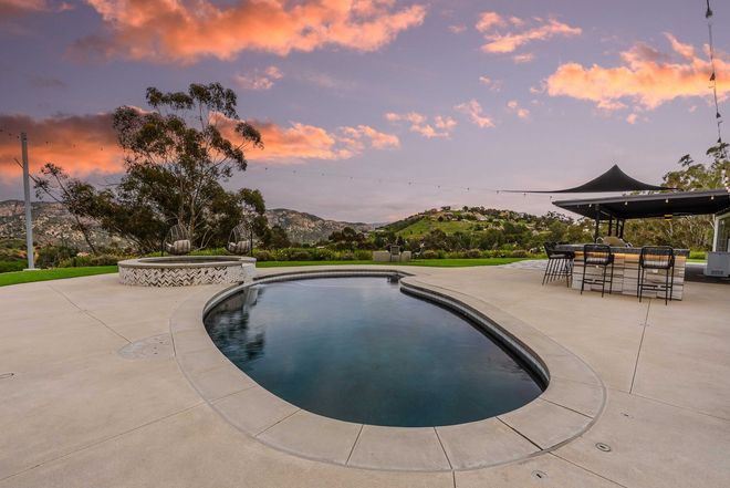 Swimming pool patio overlooking hills at sunset.
