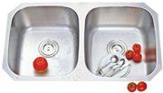 A stainless steel kitchen sink with tomatoes and utensils in it.