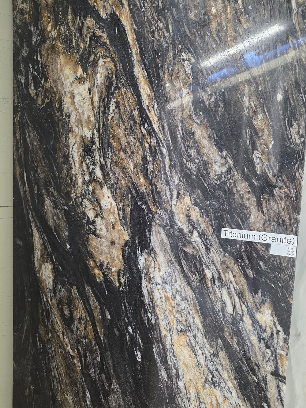 A close-up view of polished stone tile featuring a marbled pattern of black, white, and tan veins.