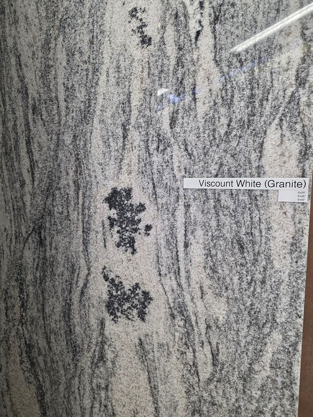 A vertical slab of Viscount White granite with wavy grey, black, and white mineral patterns.
