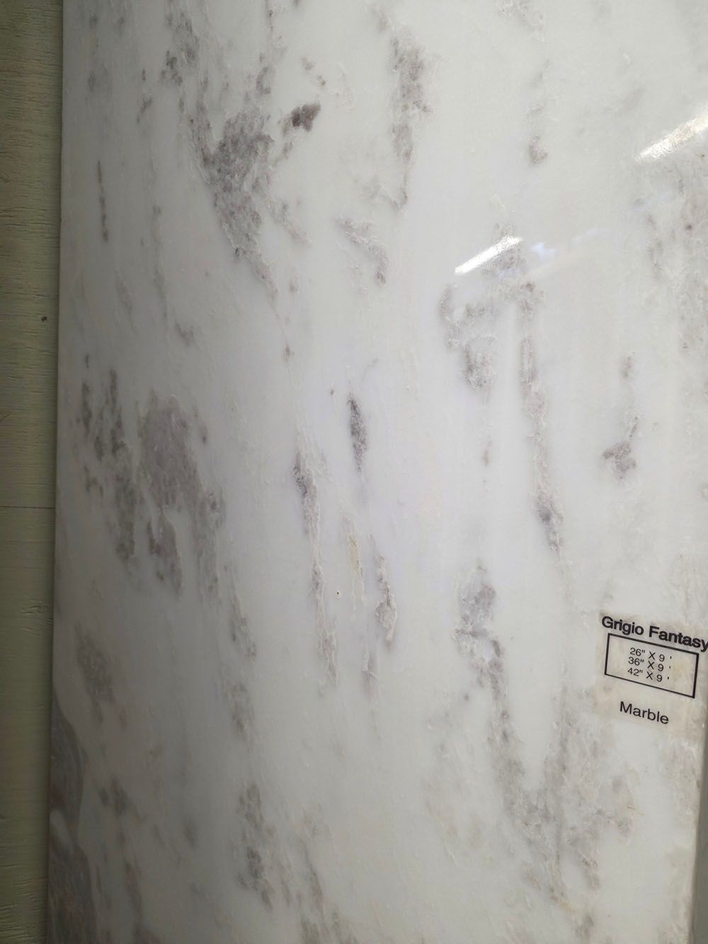 A glossy, white polished tile featuring subtle, organic gray and taupe marble-like veining patterns throughout.