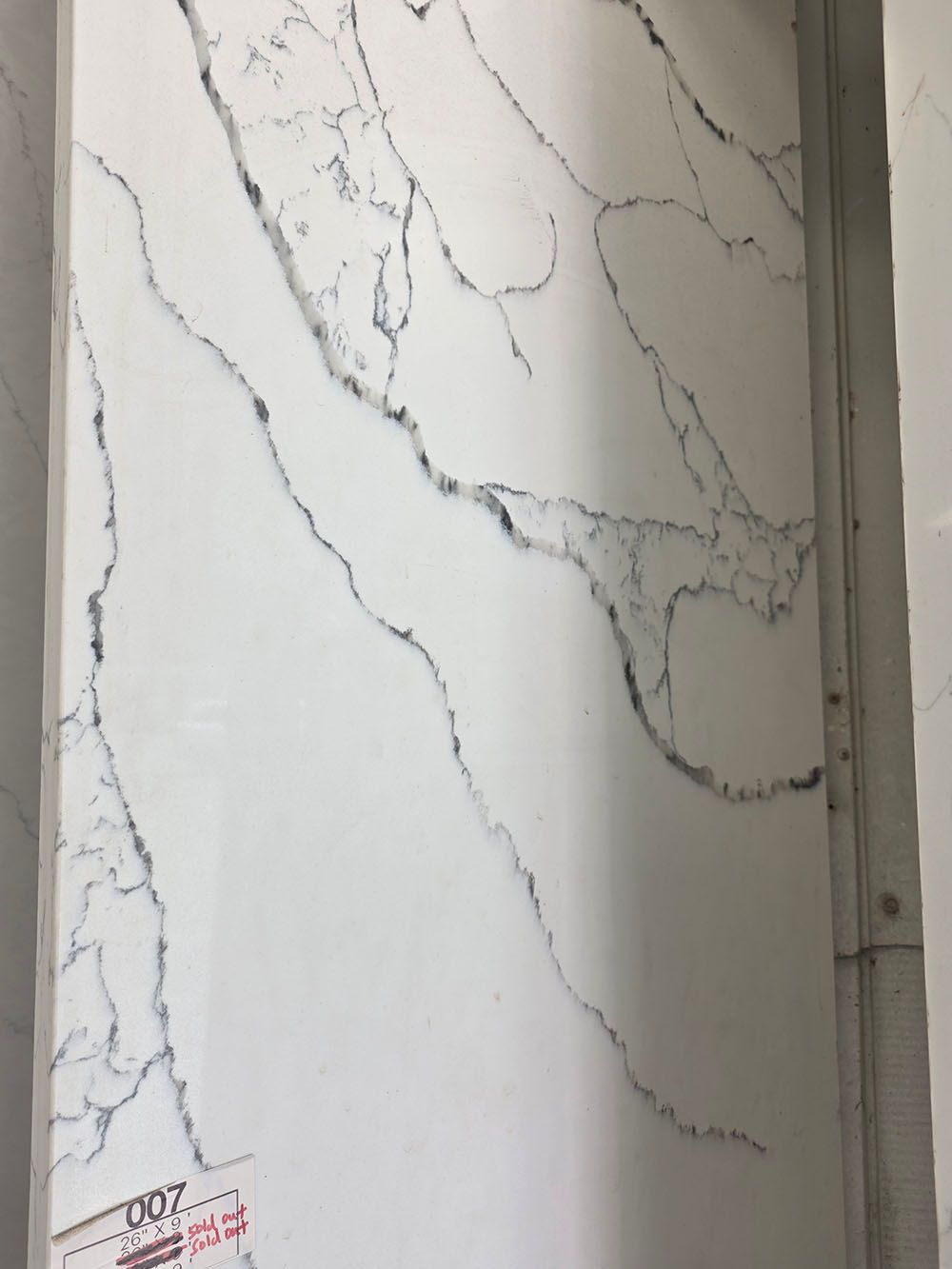 A slab of white quartz countertop material with prominent, dramatic dark grey and black veining patterns.