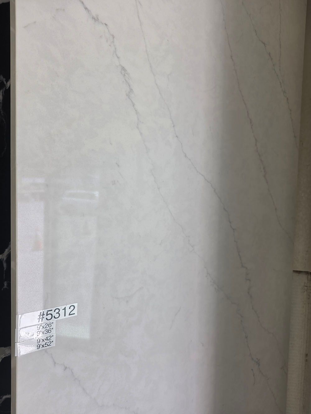 A rectangular, polished white porcelain tile with light grey marble-style veining.
