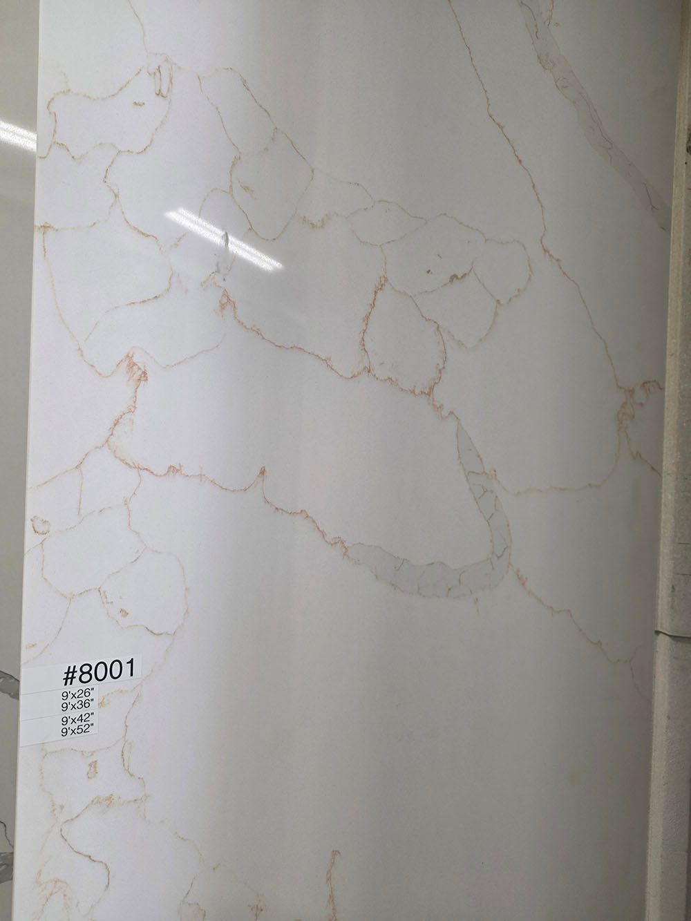 A white slab with a polished finish and prominent, irregular gold-toned marble veining throughout the surface.
