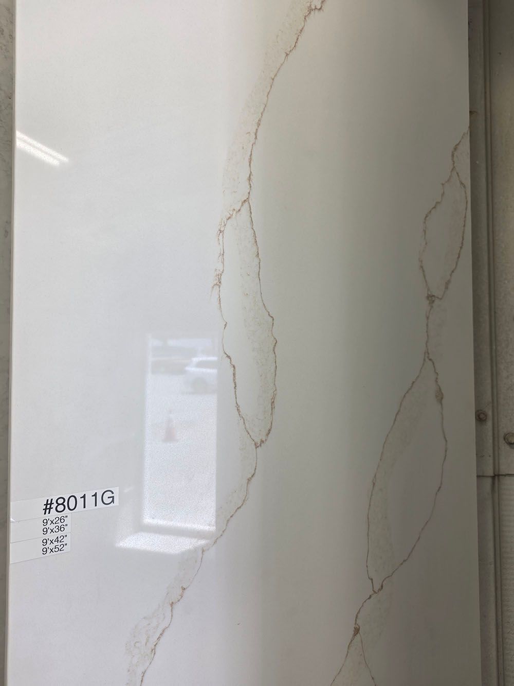 A vertical slab of white quartz with thin, light brown veining.