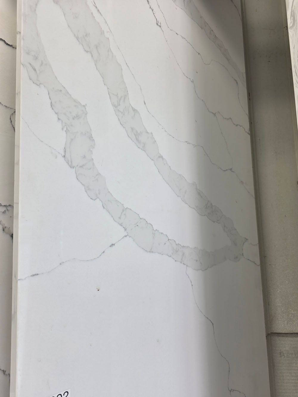 A white slab of quartz countertop featuring soft, sweeping grey veining.