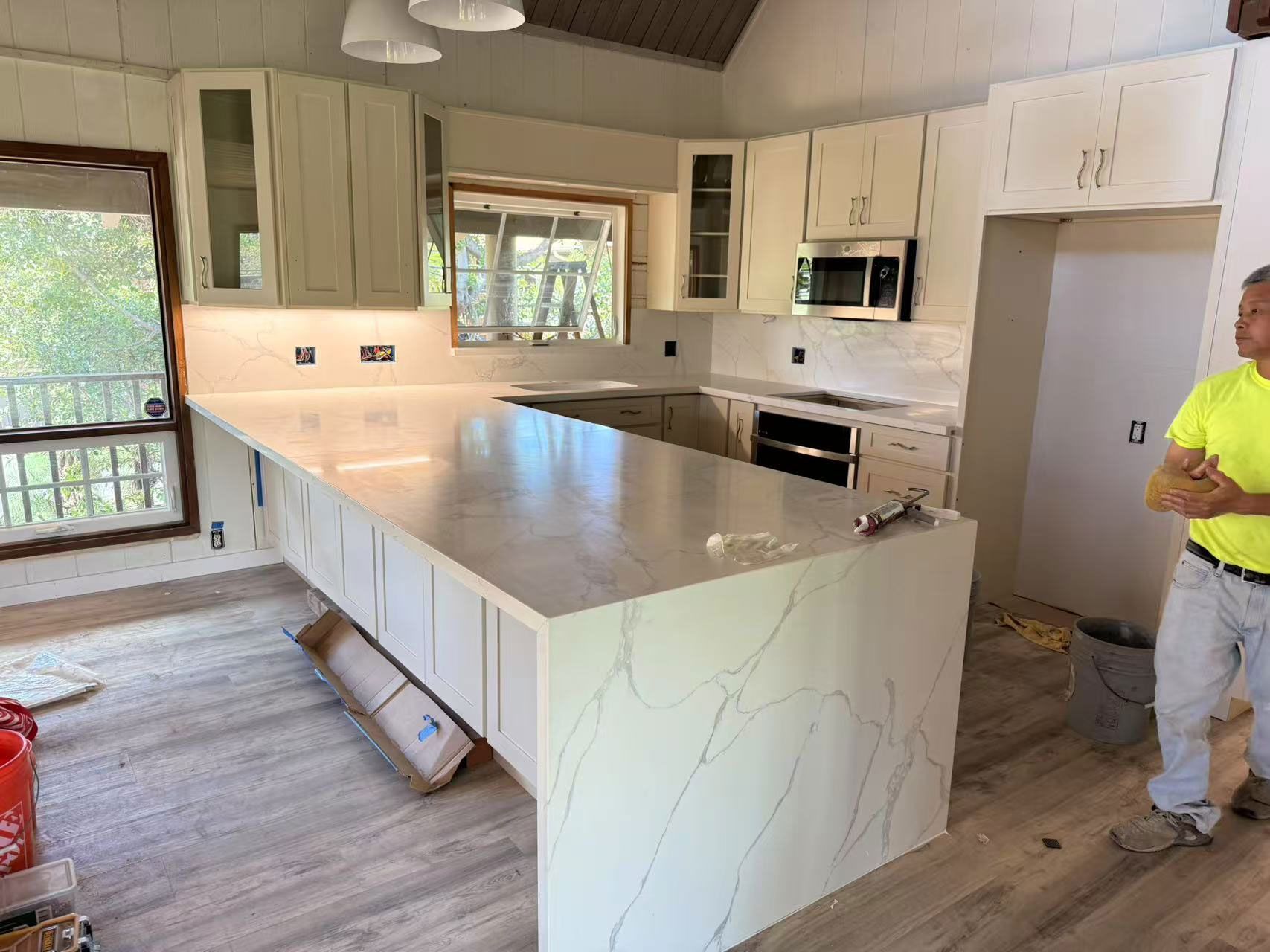A man is standing in a kitchen with a large island.
