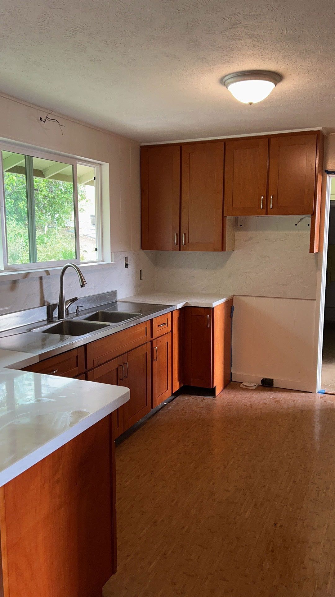 An empty kitchen with wooden cabinets and a sink.