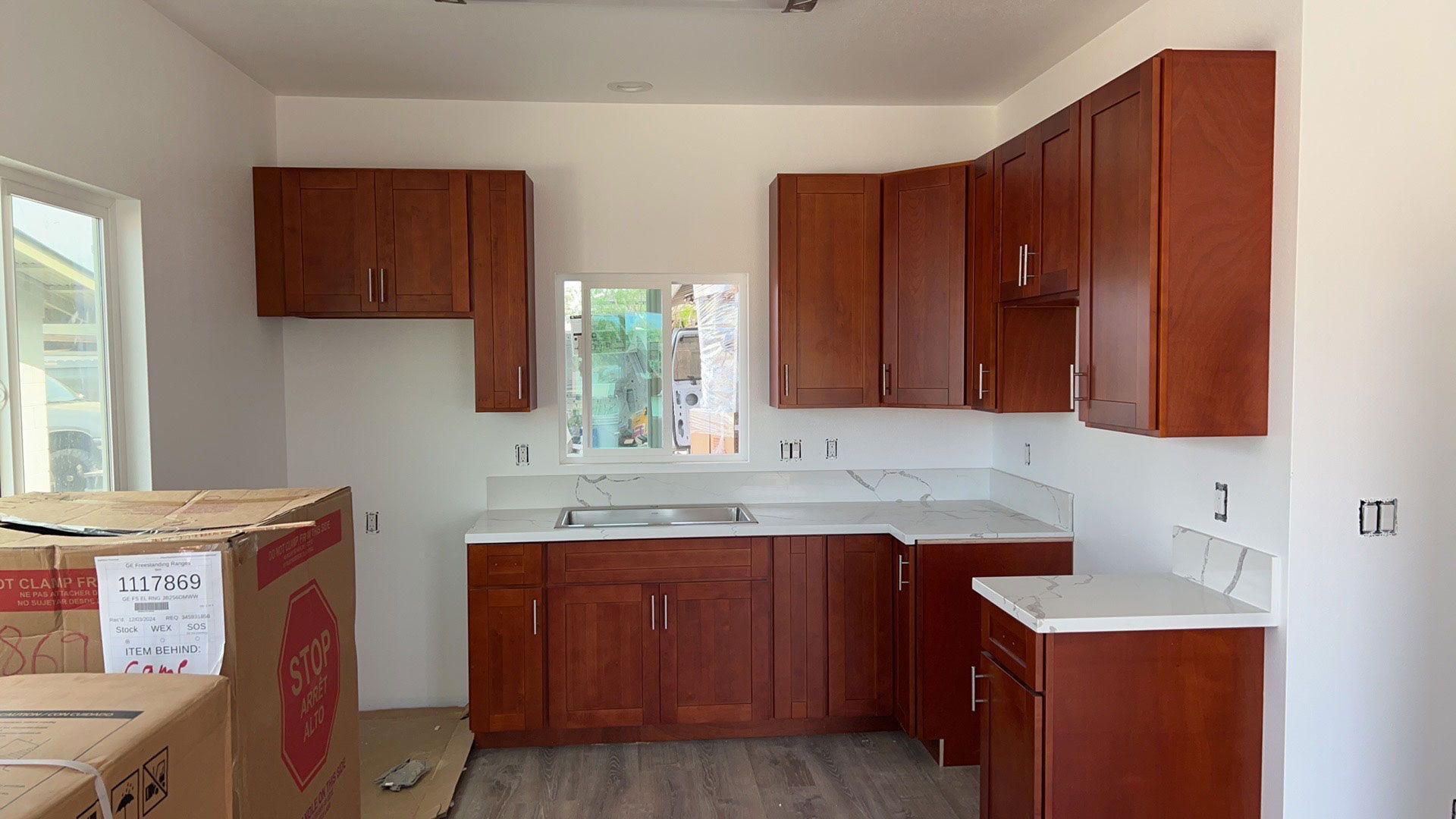 A kitchen with wooden cabinets and white counter tops is being remodeled.