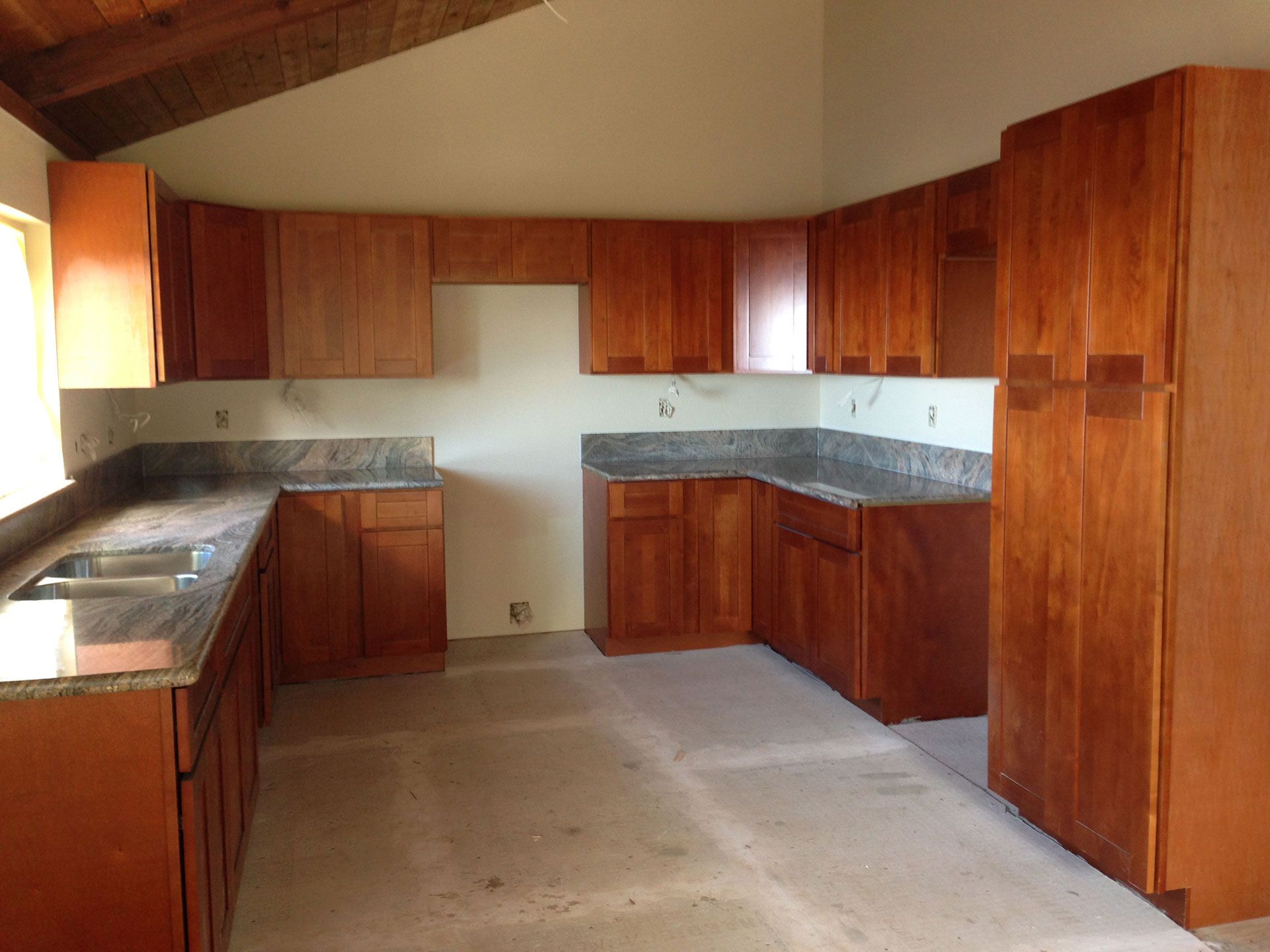 An empty kitchen with wooden cabinets and granite counter tops