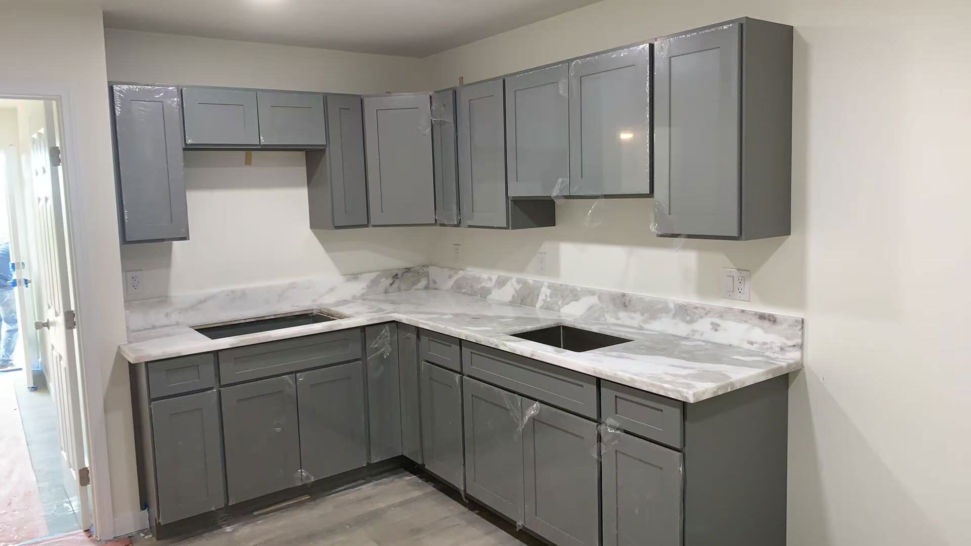 A kitchen with gray cabinets and marble counter tops.