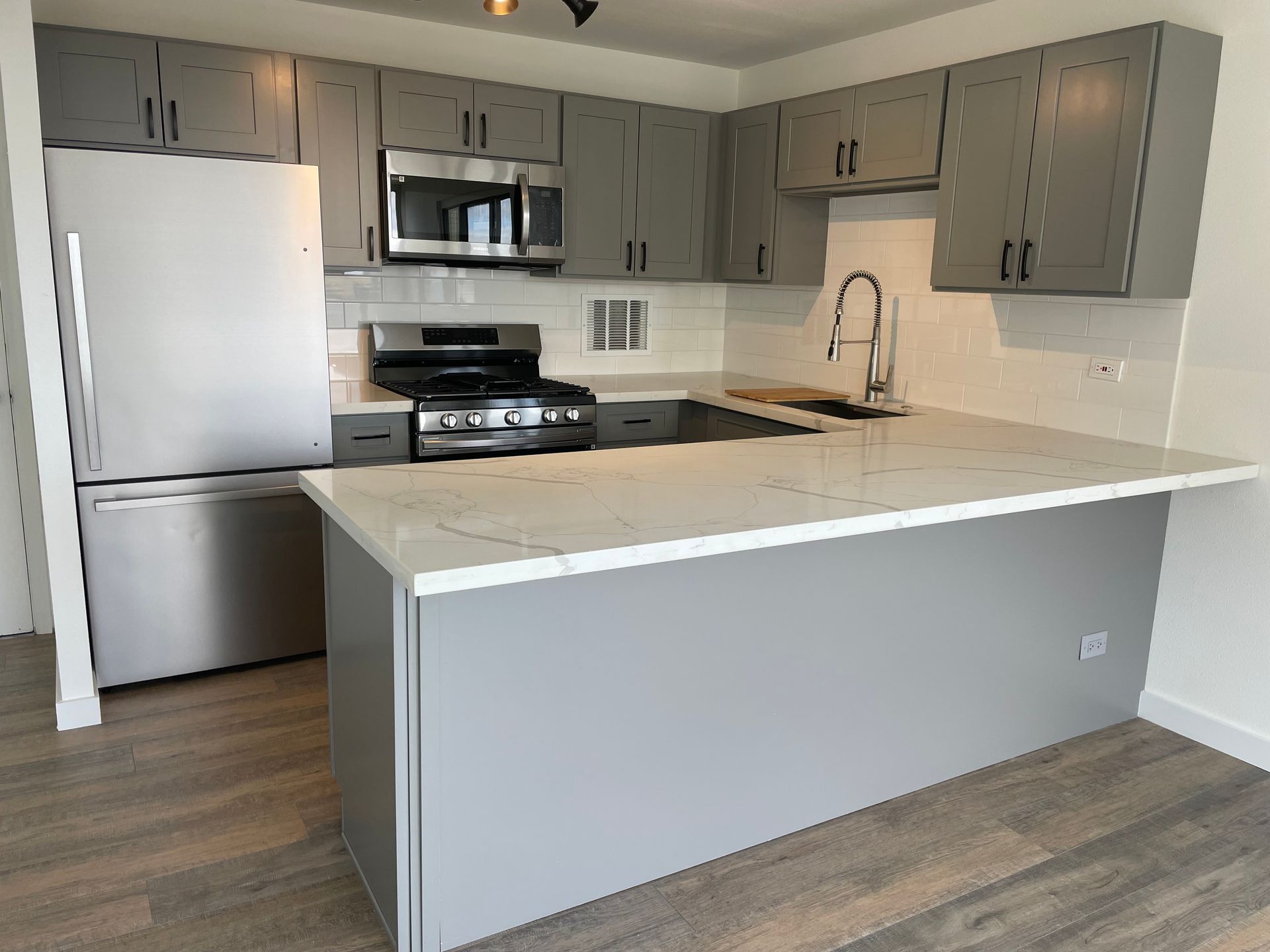 A kitchen with stainless steel appliances and gray cabinets.