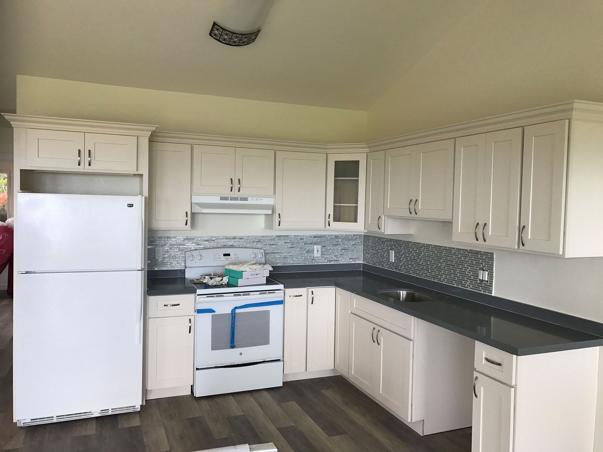 A kitchen with white cabinets, a refrigerator, a stove, and a sink.