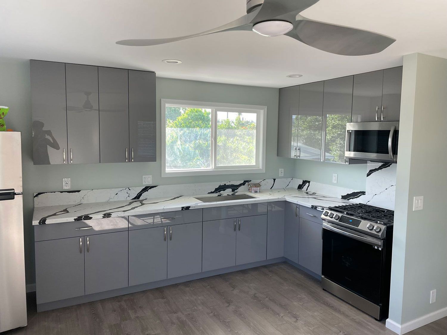 A kitchen with gray cabinets, stainless steel appliances, and a ceiling fan.