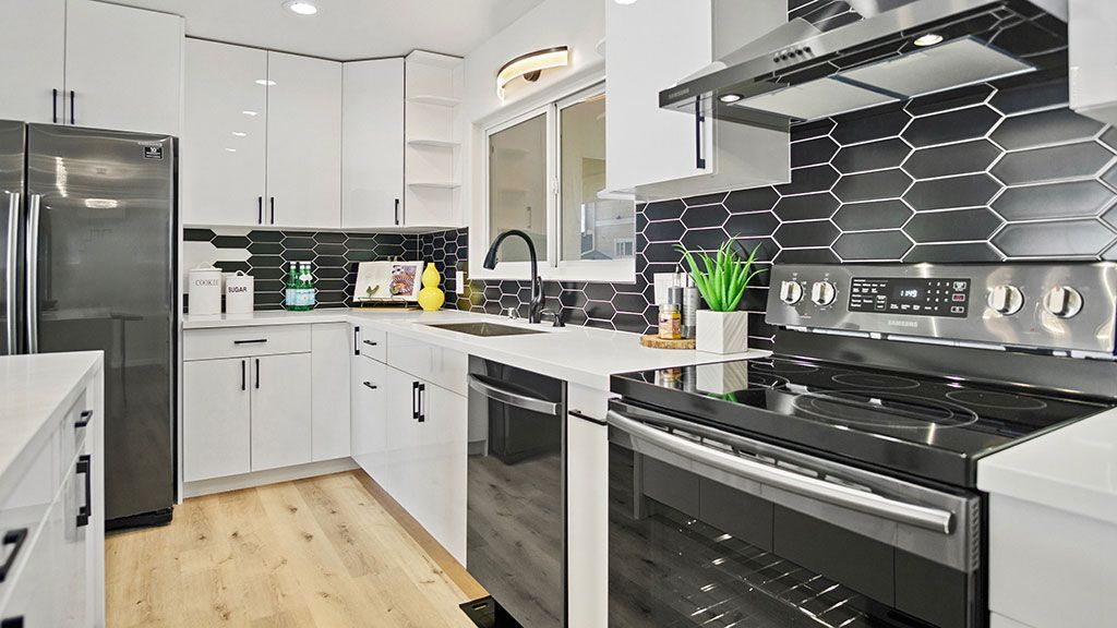 A kitchen with black and white tiles, stainless steel appliances, and white cabinets.