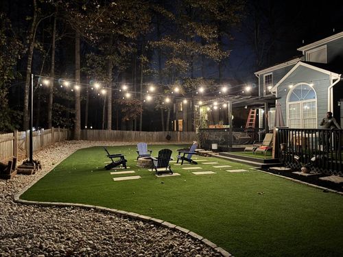 Wooden deck with pergola, overlooking a green yard and trees.