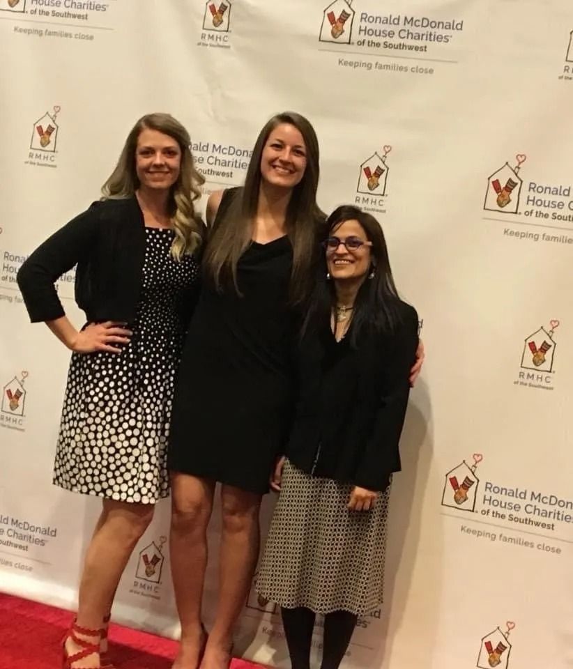 Three women smiling at a Ronald McDonald House Charities event on a red carpet.