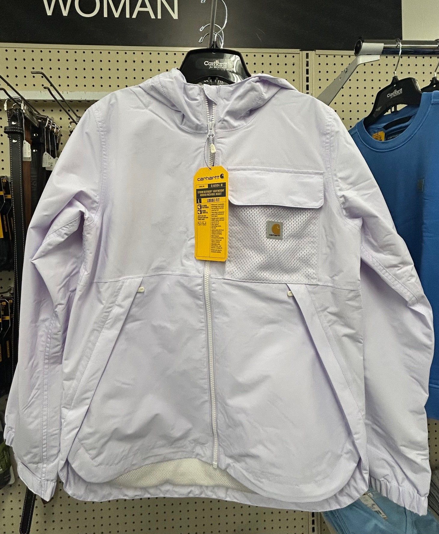 A white carhartt jacket is hanging on a rack