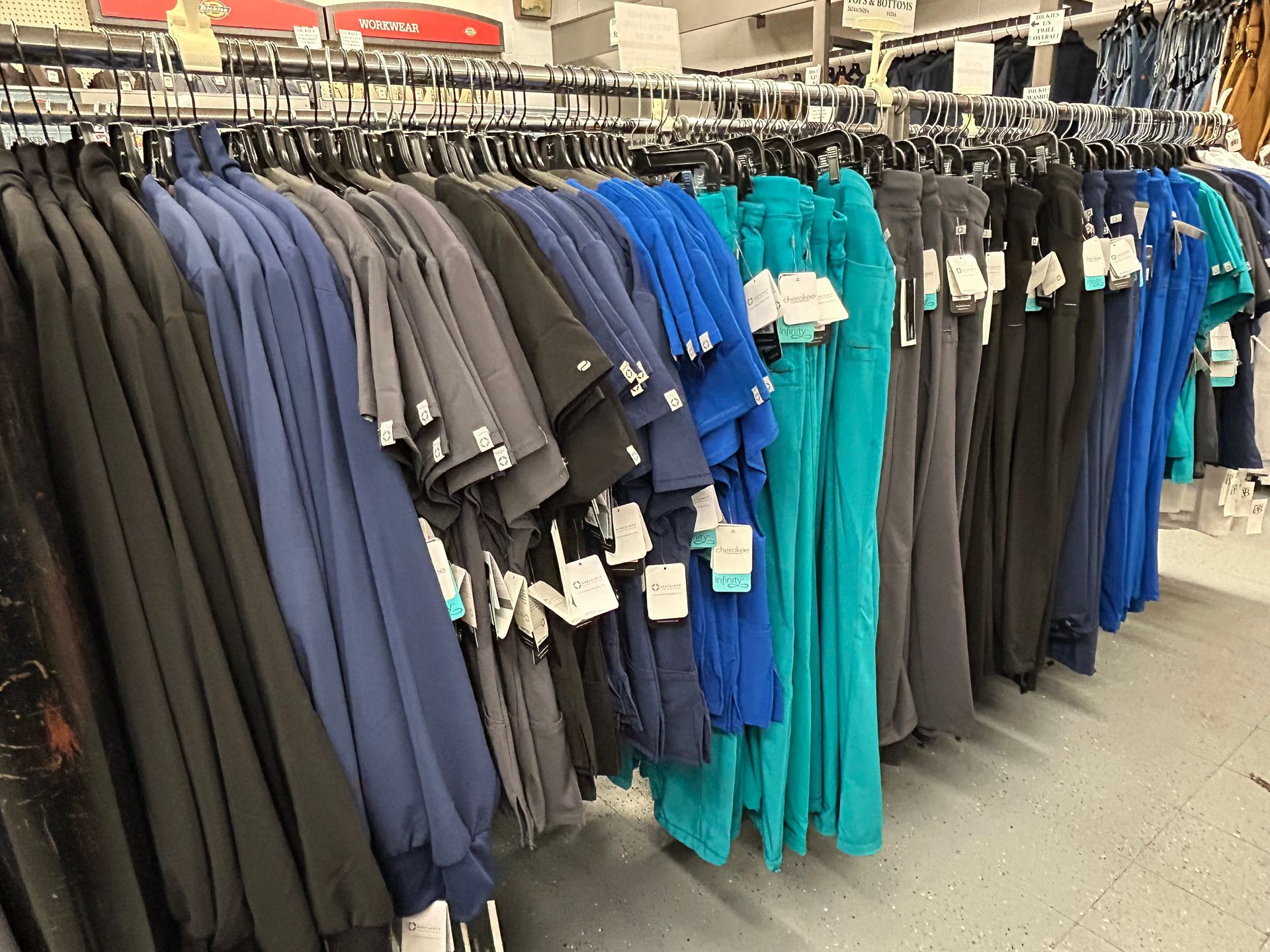 A row of scrubs hanging on a rack in a store.