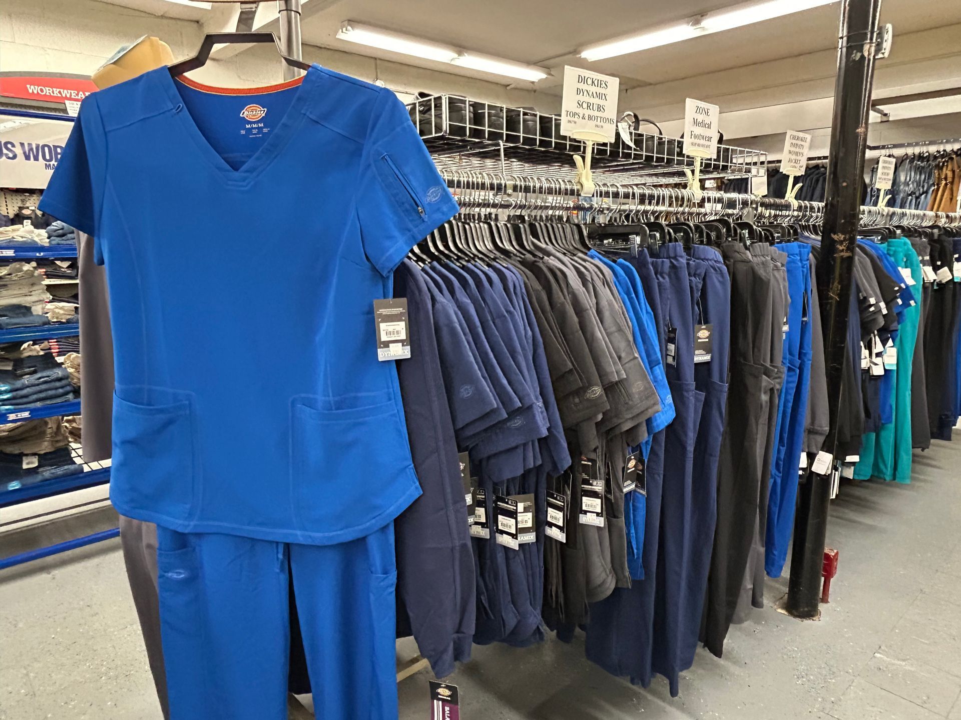 A blue scrub suit is hanging on a rack in a store.