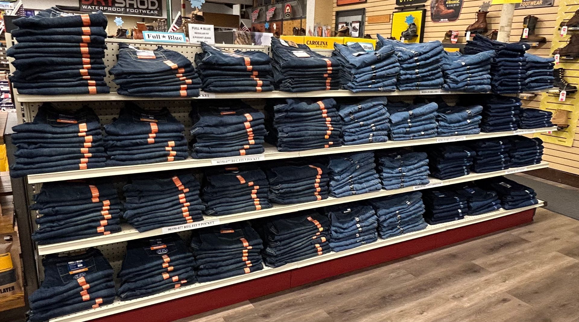 A shelf filled with lots of stacks of jeans in a store.