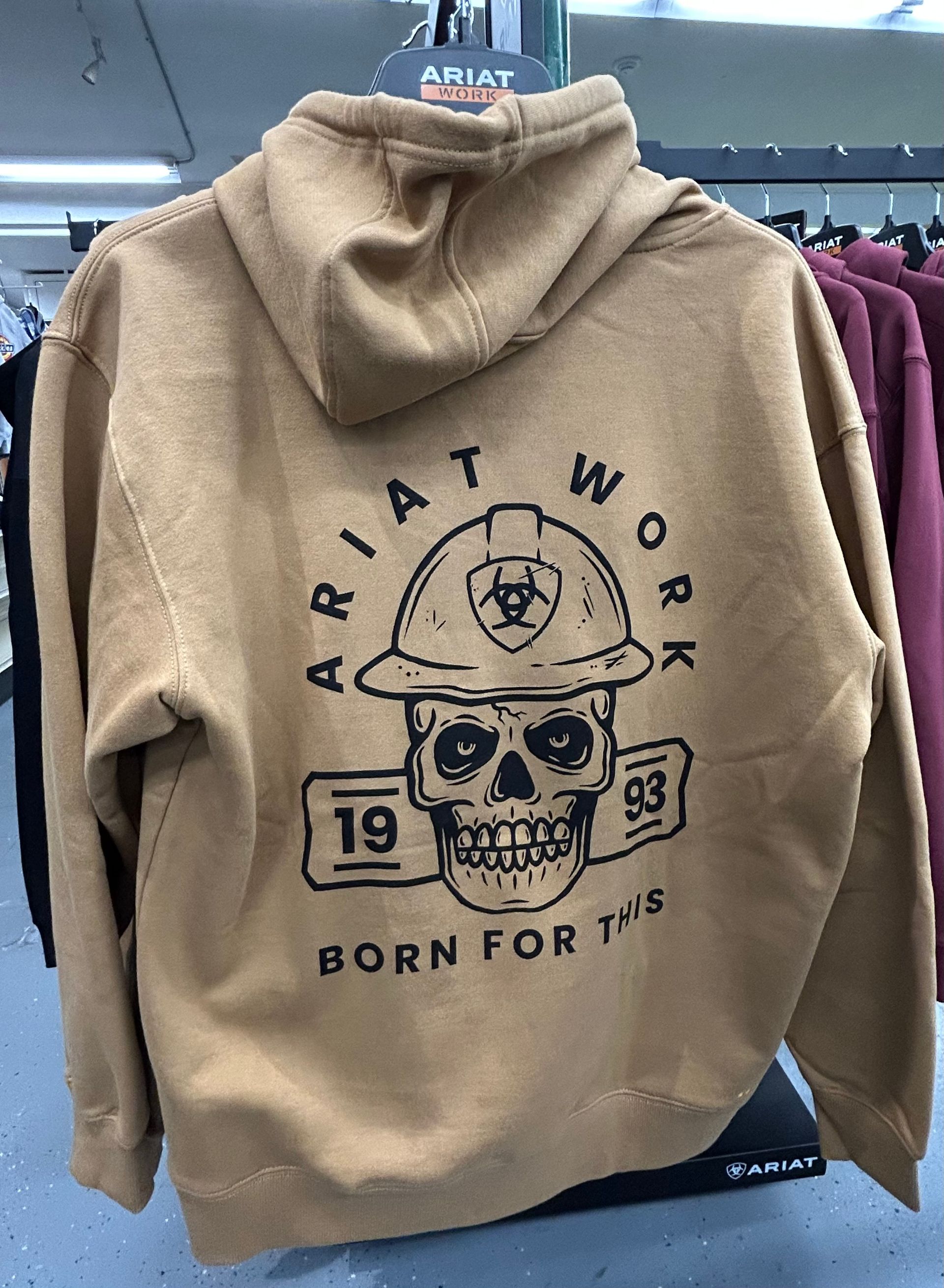 A hoodie with a skull on it is hanging on a rack in a store.