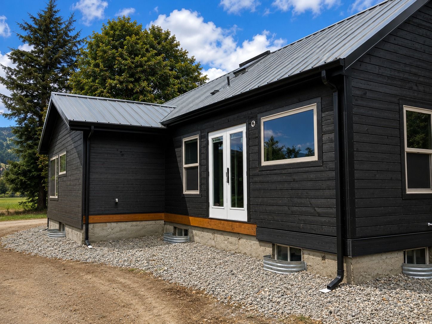 Black seamless gutters and downspouts installed on remodeled Everson WA home with metal roof
