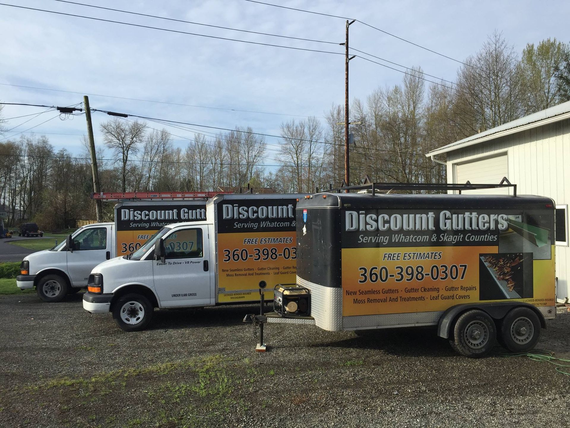 Trucks and trailer advertising Discount Gutter parked by a roadside in daylight