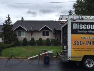 Large yellow-and-white service truck parked in front of a house on a cloudy day.