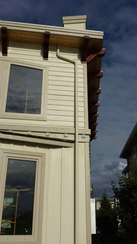 White house exterior with large windows and decorative roof trim against a cloudy sky