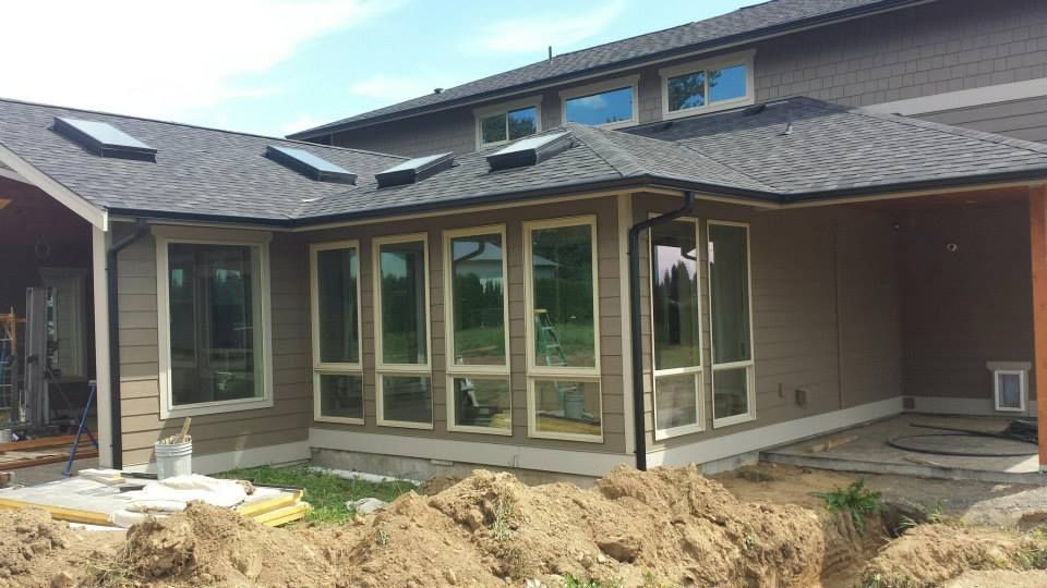 New home exterior with large windows and exposed dirt during construction
