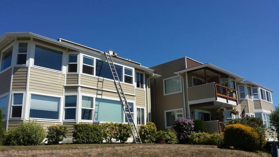 Two-story beige apartment buildings with balconies under a clear blue sky