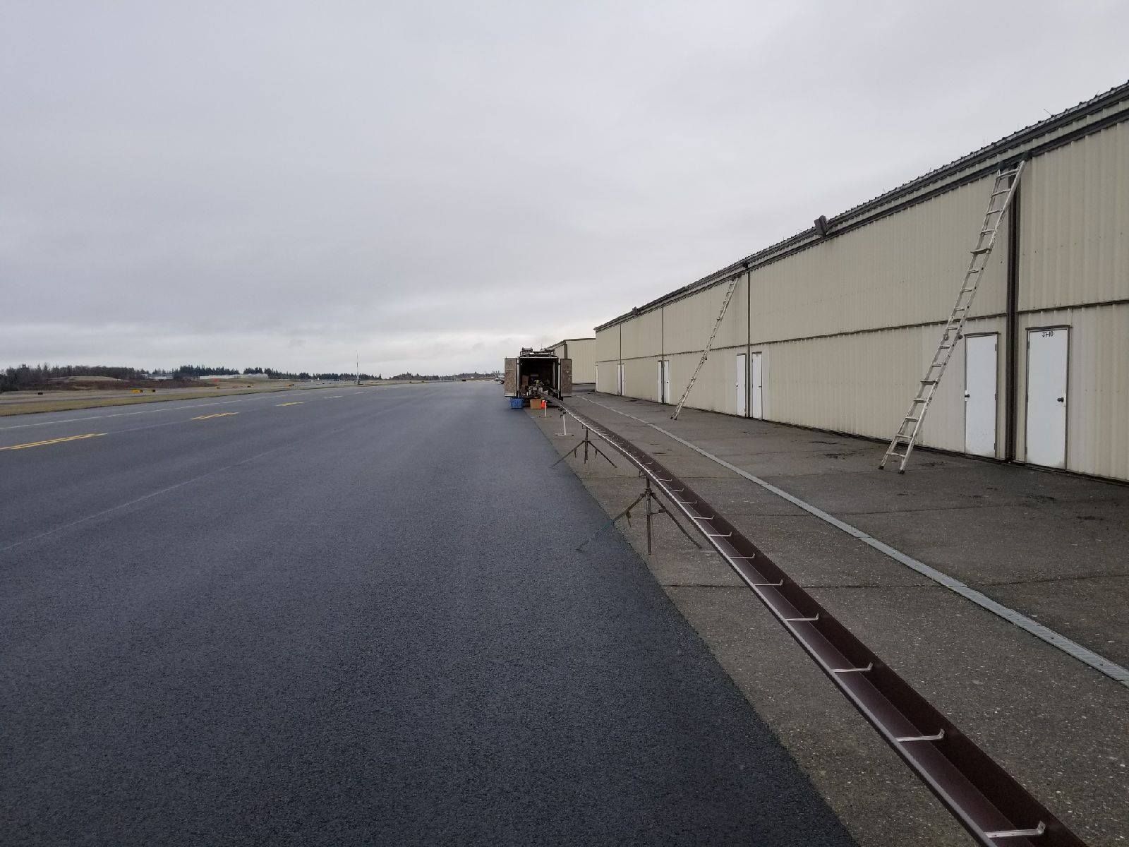 Empty airport tarmac beside a long hangar under an overcast sky