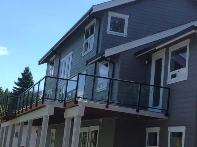 Modern gray house with a raised glass-railed deck and white support columns