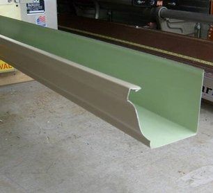 Long green metal gutter or channel beam lying on a workshop floor
