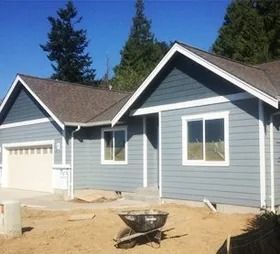 New gray-blue house with white trim and garage under construction on a sunny day