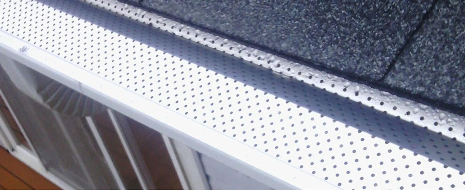 Close-up of a white perforated metal edge beside a dark countertop and window frame
