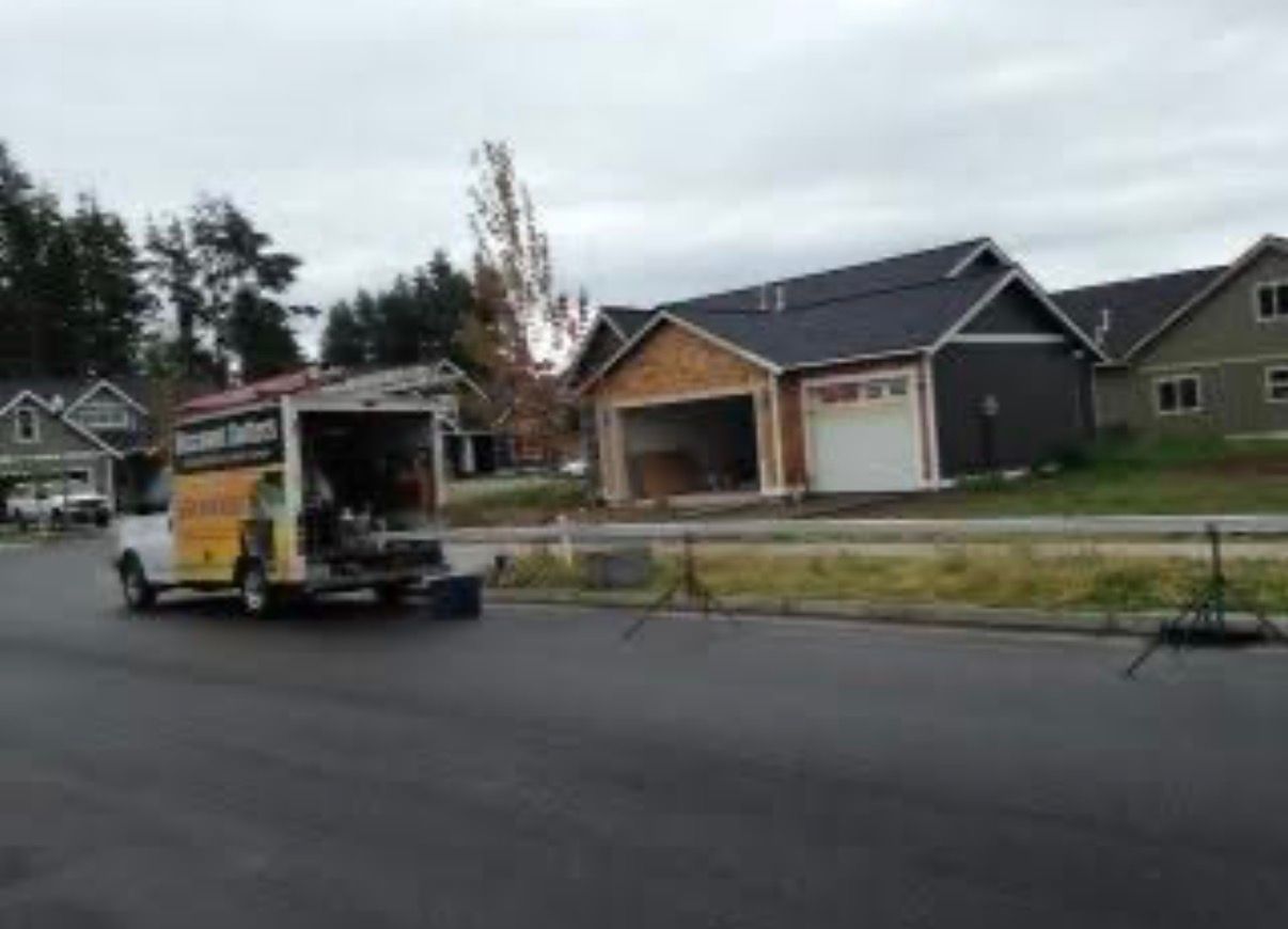 Tow truck loading a white van on a suburban street with houses in the background