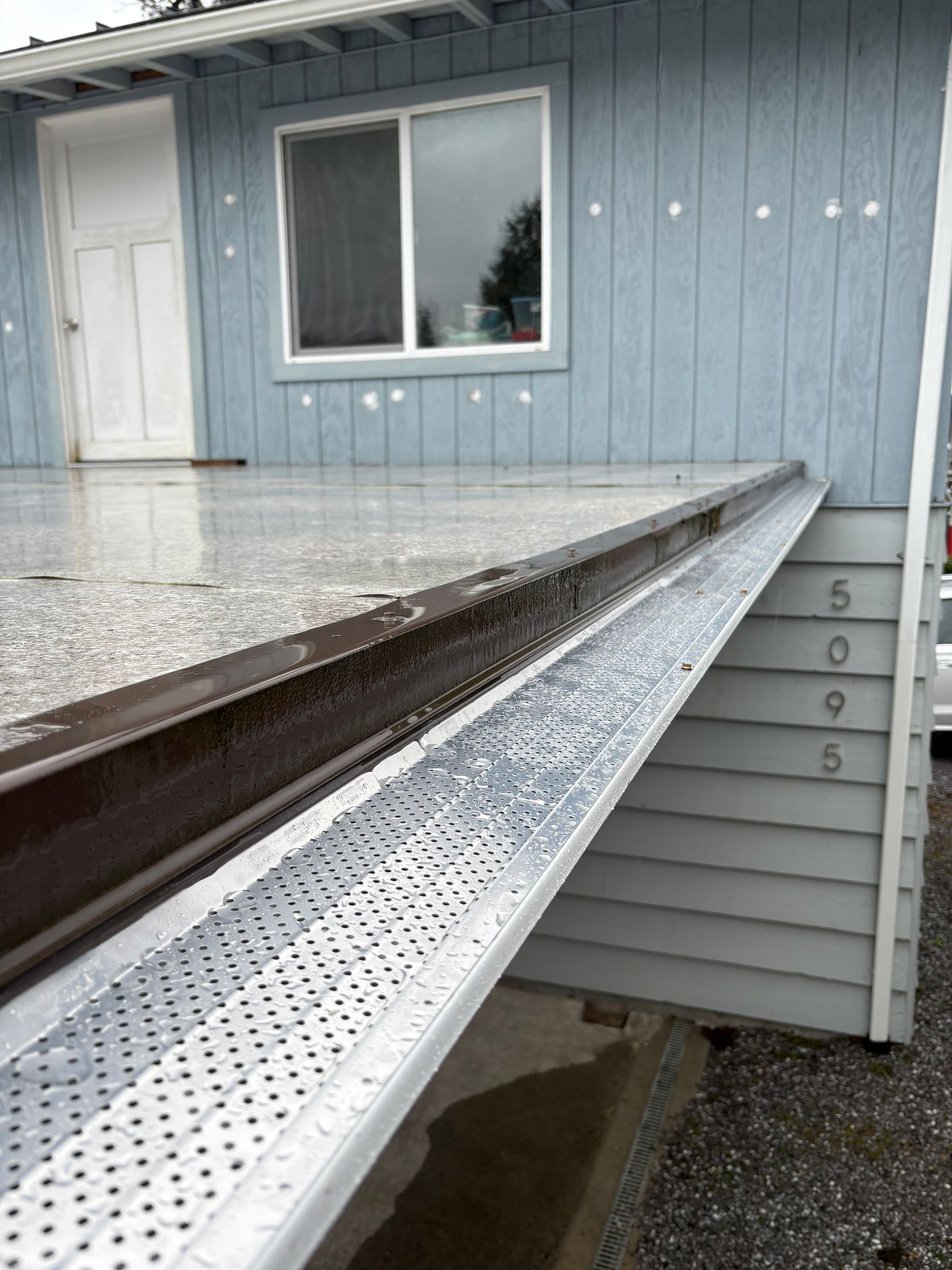 Steep metal ramp leading to a house entrance with a blue exterior wall and window
