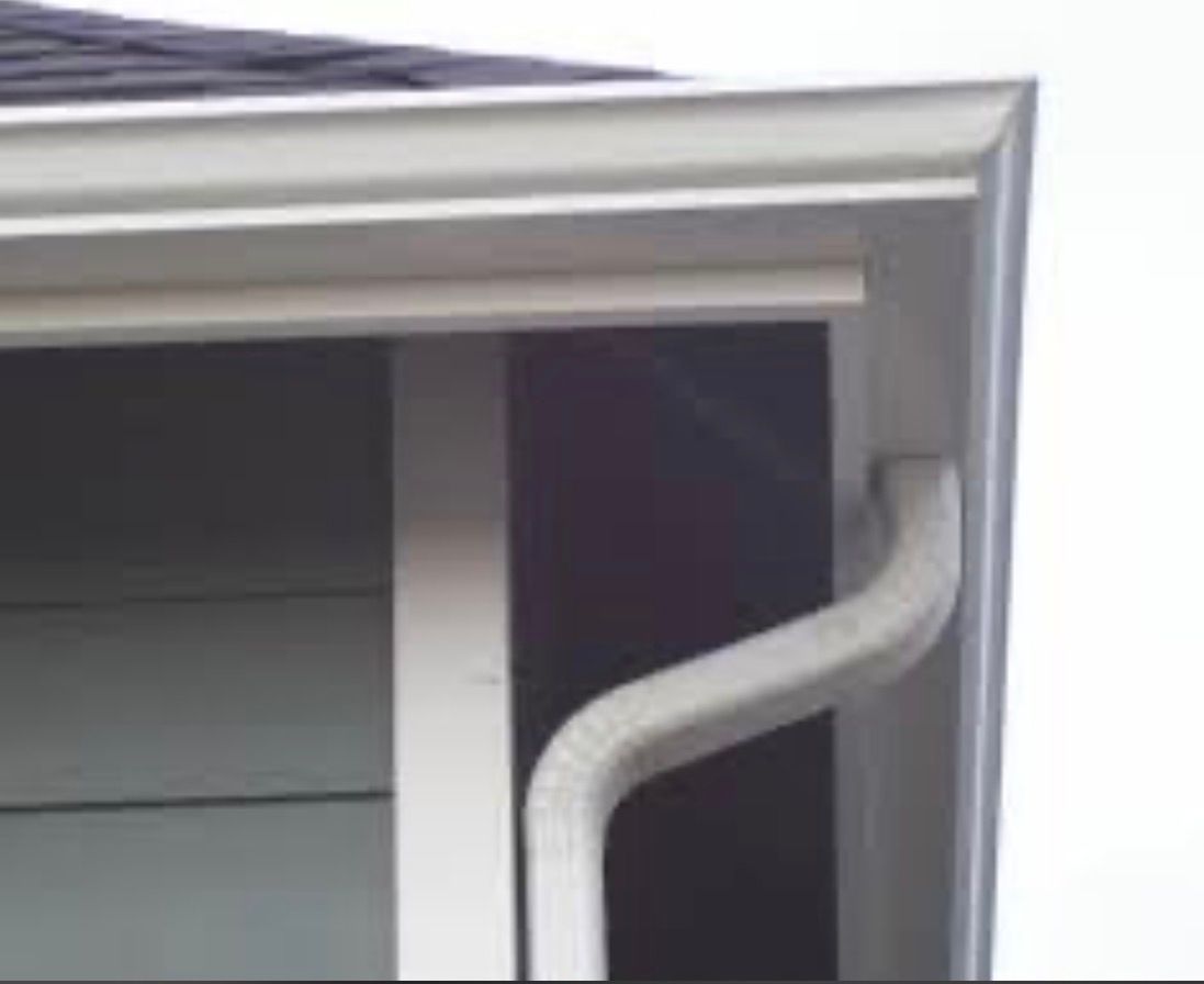 White gutter downspout attached to the corner of a house roof.