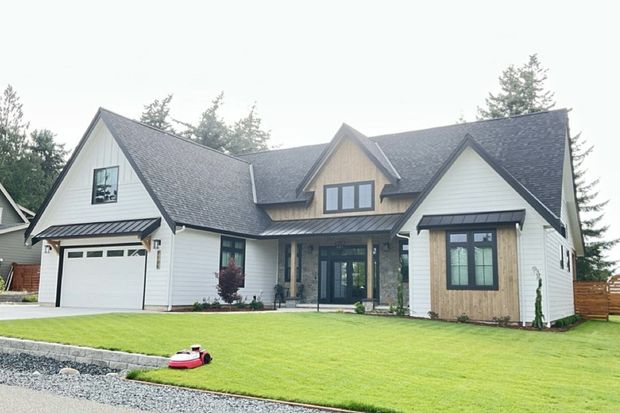 Large suburban house with gray roof, white siding, and a green lawn