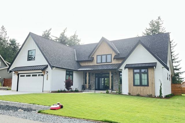 Large suburban house with gray roof, white siding, and a green lawn