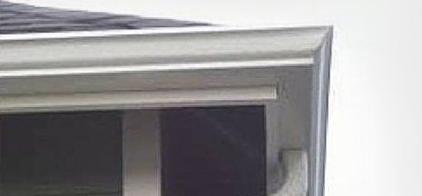 Close-up of a metallic window or door frame with glass panels and a white wall corner
