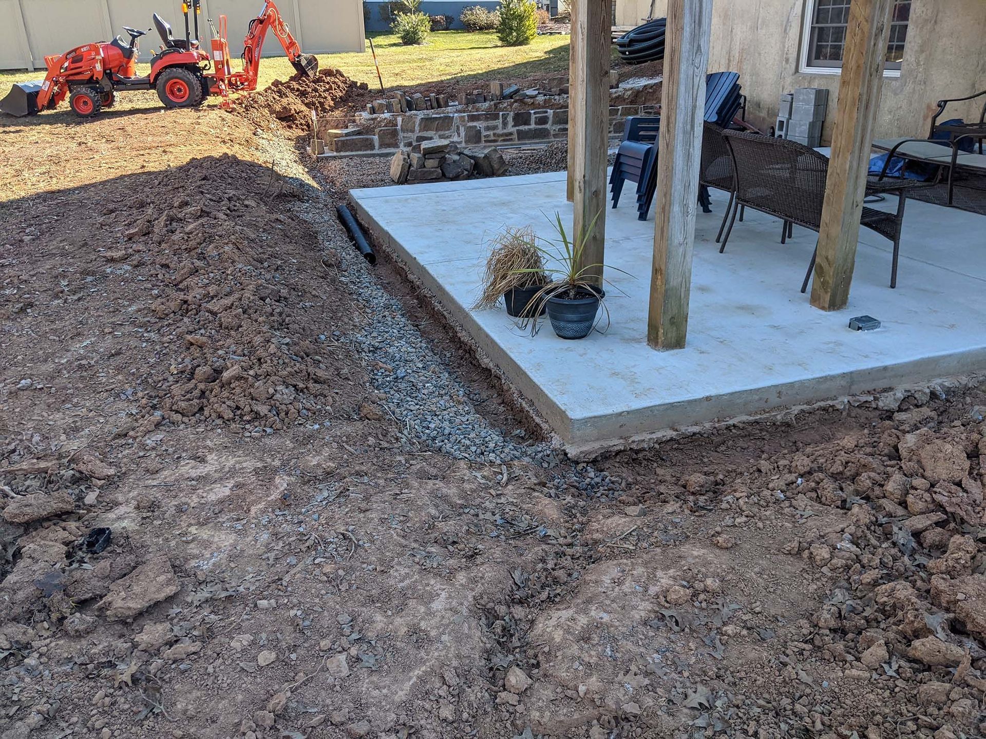 Excavation site with a concrete patio. A small tractor is visible.